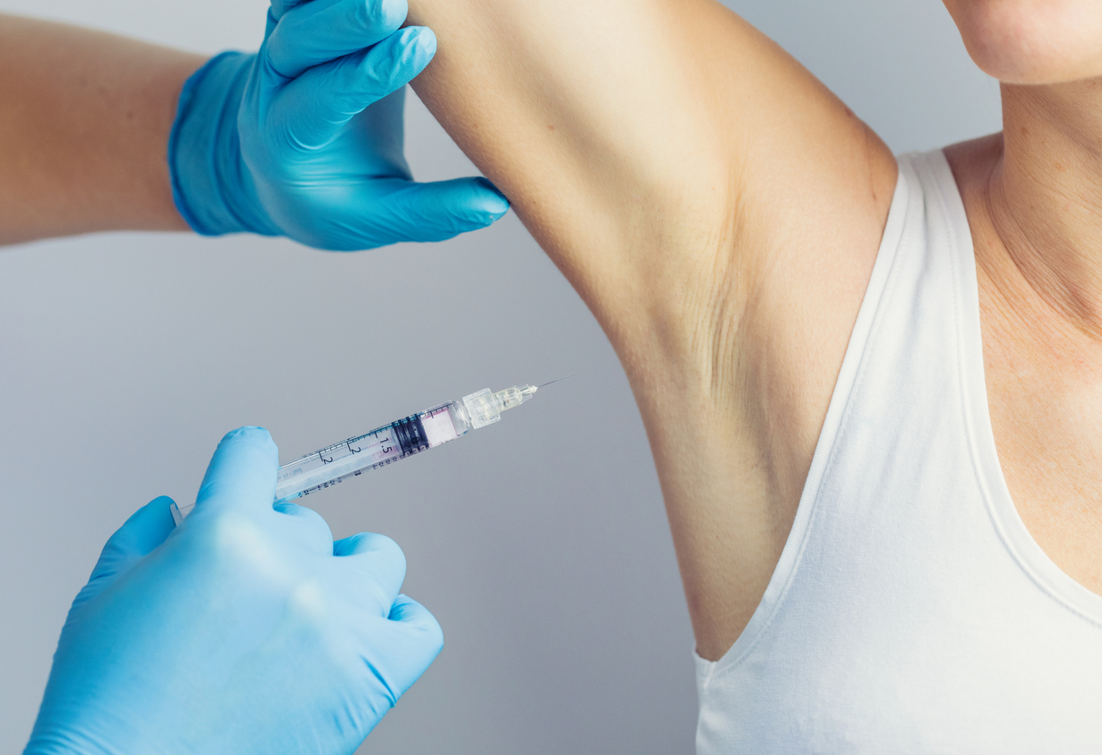 Close-up photo of doctor making intramuscular injection of botulinum toxin in the armpit to reduce sweating