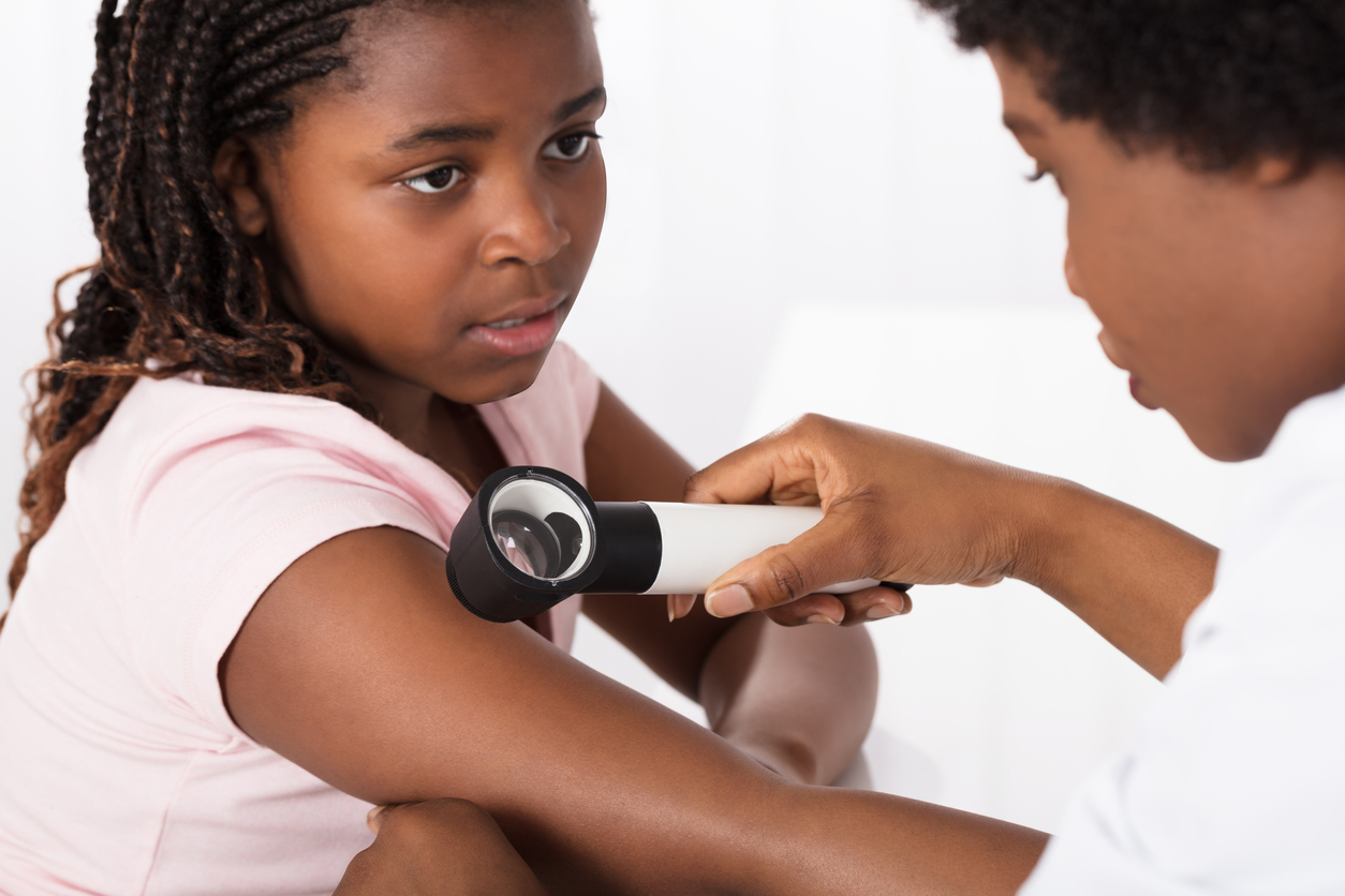 Female Doctor Examining Skin Of Girl With Dermatoscope In A Clinic